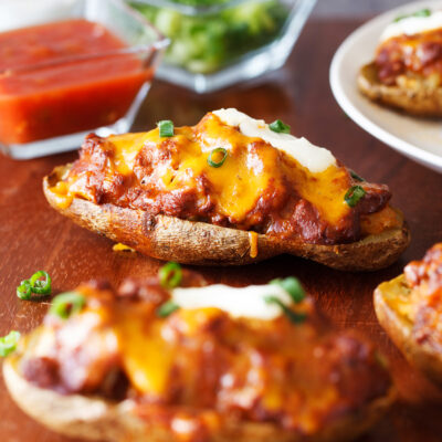 Chili Cheese Stuffed Potato Skins consist of an entire russet potato half, are loaded with a hefty filling, and finished off with mouthwatering toppings.